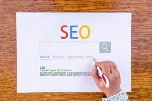 Person highlighting SEO-related terms on a printed search engine interface illustration, symbolizing keywords, optimization, and traffic strategies for website development in Jupiter, Florida.